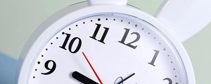 Close-up of minimalist white bunny alarm clock featuring black numbers and red second hand