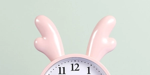 Detail of cute pink alarm clock featuring elk antlers and clear black Arabic numerals