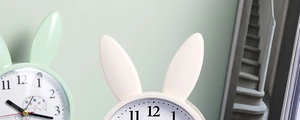 Close-up detail of the creative rabbit ears on light green and cream silent alarm clocks