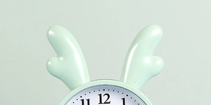 Close-up of the light green alarm clock with cute antlers and smooth plastic finish