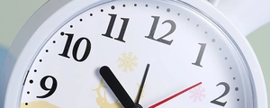 Close-up of a white clock face featuring black numerals and red second hand with deer motif