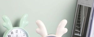 Close-up of minimalist round alarm clock with antler decor and mint green background