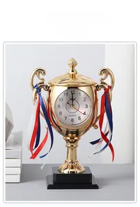 Detail of a gold trophy-shaped alarm clock with tricolor ribbons on a study desk