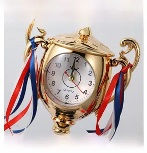 Detailed macro shot of a golden trophy-shaped desk alarm clock with ornate handles and ribbon