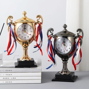 Creative trophy-shaped desk alarm clock in gold and gunmetal with decorative ribbon