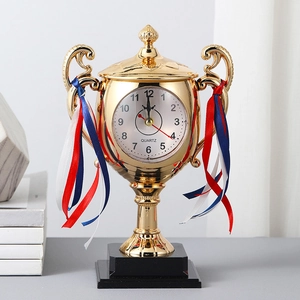 Creative trophy-shaped desk clock with gold metallic finish and decorative ribbons