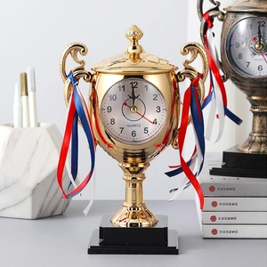 Creative gold trophy desk clock with tricolor ribbons and black base on a study desk