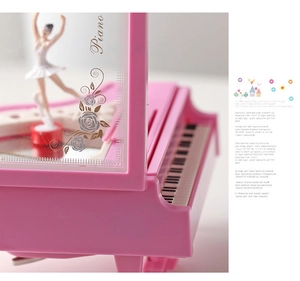 Close-up of a pink piano music box featuring a ballerina figure and detailed keys