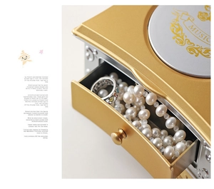 Vue détaillée du tiroir de la boîte à bijoux musicale dorée avec perles et rangement