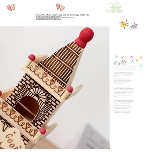 Macro detail of laser-cut wooden windmill music box showing fine textures and red accents