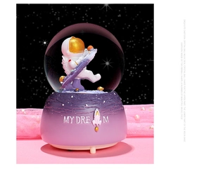 Close-up of astronaut crystal ball music box with My Dream resin base and purple glitter