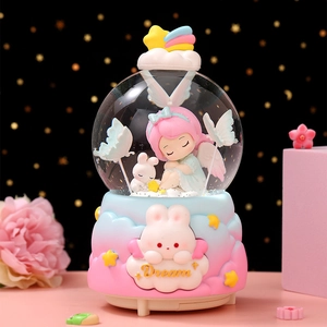 Close-up of snow globe featuring sleeping angel girl and rabbit with Dream relief base
