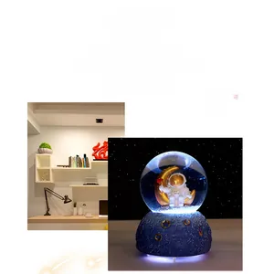 Detail of astronaut on gold moon inside a crystal ball music box with starry base