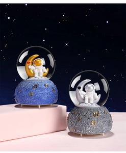 Detailed view of astronaut crystal ball music boxes with textured lunar crater bases