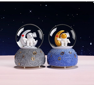 Detail of two astronaut crystal balls with silver and gold moons on textured bases