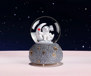 Detailed view of an astronaut figurine on a silver moon inside a glowing glass crystal ball