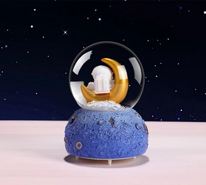 Detailed close-up of astronaut crystal ball featuring a gold moon and crater base