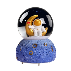 Astronaut snow globe music box with astronaut on gold moon and blue moon textured base