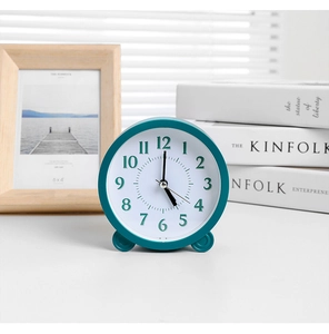 Close-up of a minimalist teal round silent desk clock with two spherical stands