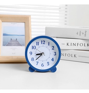 Close-up of minimalist blue alarm clock with 3D numerals on a wooden desk setup
