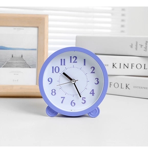 Close-up of minimalist light purple round alarm clock with clear Arabic numerals on a desk