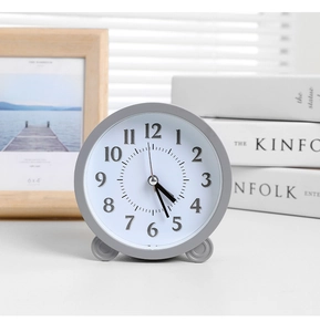 Detail of minimalist gray table clock with Arabic numerals on wood tabletop