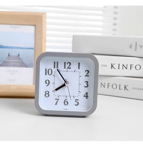 Minimalist gray square desk clock with silver numbers on a modern wooden table