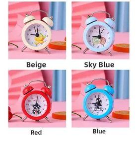 Close-up of four mini alarm clocks in beige, blue, and red with cartoon dial patterns