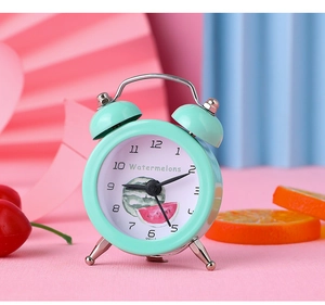 Macro detail of mint green mini alarm clock featuring watermelon patterns and metal stand