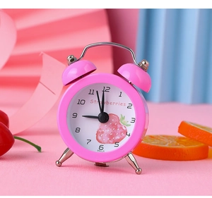 Macro shot of pink mini strawberry alarm clock with metal twin bells and white dial