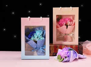 Three colors of artificial soap flower bouquets in transparent gift bags with ribbons