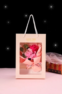 Detail view of artificial rose and carnation bouquet in a pink gift bag with transparent window