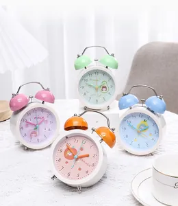 Detail of four macaron-colored alarm clocks with fruit illustrations on a lace tablecloth
