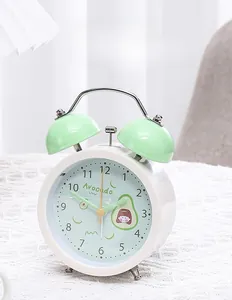 Detail of mint green double bell alarm clock featuring a cute avocado dial on lace cloth