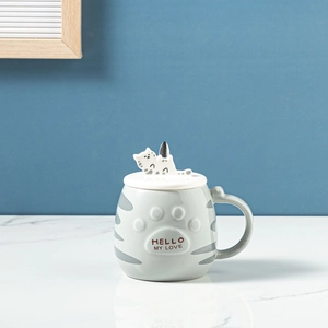 Close-up of a cat ceramic mug with a lid featuring a cute cat head and a mixing spoon
