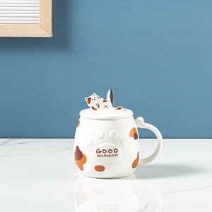 Macro shot of ceramic cat mug featuring a lid with a 3D cat figure and a metal stir spoon