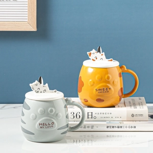 Detail of ceramic cat mugs with 3D figurines on lids and cute paw relief patterns