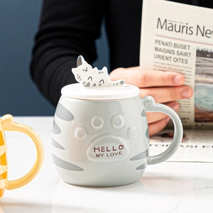 Close-up of cat ceramic mug with 3D kitty lid handle and embossed paw pattern