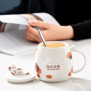 Close-up of cat paw ceramic mug set with 3D cat lid and spoon on a morning table