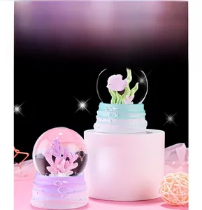 Detail of glowing ocean crystal ball with pink fish and coral inside a resin base