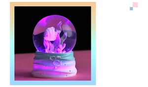 Detail of glowing ocean crystal ball with fish, pink corals and purple LED light