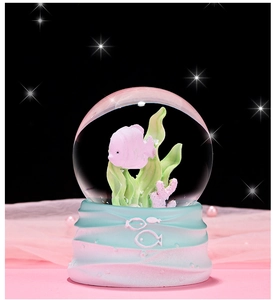 Close-up of ocean crystal ball featuring pink fish, green seaweed, and wave base detail