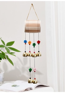 Détail d'un carillon en bois avec cloches en laiton et breloques de fleurs dans une maison