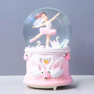 Detailed relief of pink roses and white swans on the resin base of a musical crystal ball