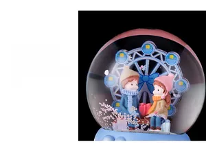 Detail showing cartoon couple figurines and blue Ferris wheel inside crystal ball