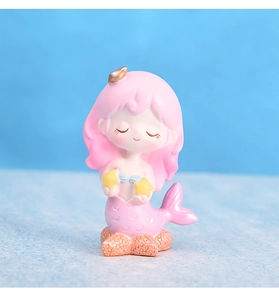 Détail d'une figurine de sirène mignonne avec queue rose sur socle de récif corallien