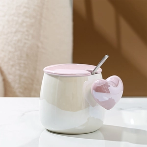Detailed view of ceramic mug featuring a unique pink heart-shaped handle and metal spoon