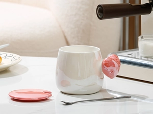 Artistic ceramic heart handle mug with matching pink lid and stainless steel stirring spoon
