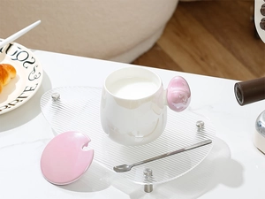 Detail of ceramic heart mug with pink spherical handle and matching lid on clear tray