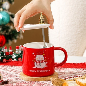 Détail macro du mug de Noël rouge avec motif bonhomme de neige et couvercle sapin doré